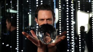 Jo Schück schaut in eine Wahrsagerkugel