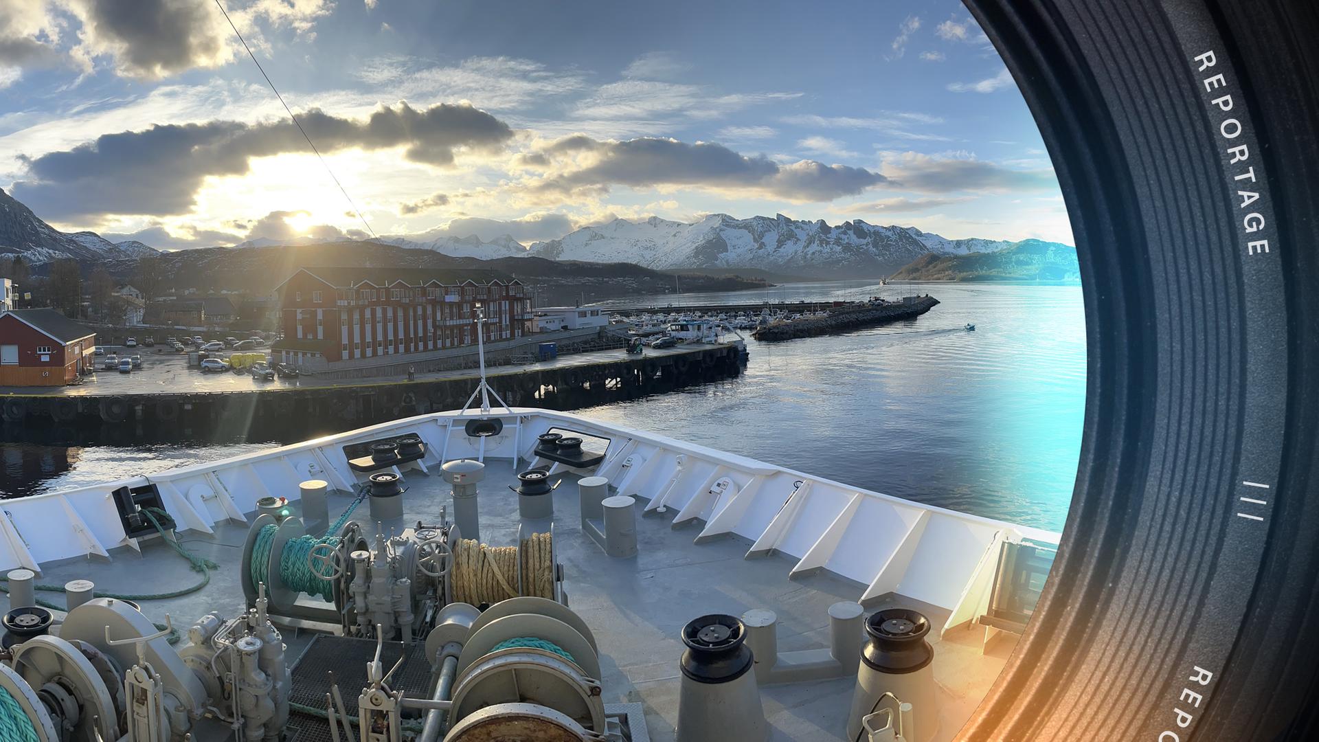 Blick vom Bug eines Hurtigruten-Schiffs auf einen kleinen norwegischen Hafen beim Anlandeprozess.