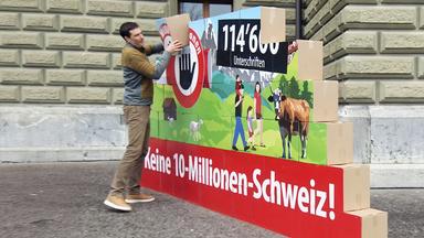 Ein öffentlicher Event, bei dem die Volksinitiative „Keine 10-Millionen-Schweiz“ der SVP eingereicht wird. Menschen sind vor einem Gebäude versammelt, um die Initiative zu unterstützen.