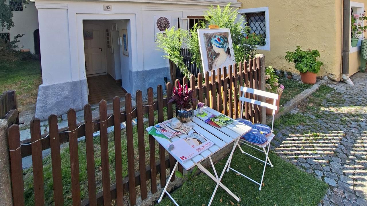 Ein gemütlicher Stuhl und Tisch stehen vor dem Atelier in Gmünd.