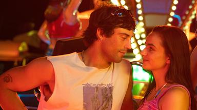 "Zwischen uns die Nacht": Erich (Aaron Altaras) und Marie (Laura Balzer) sehen sich in die Augen während Rebecca (Bea Brocks) und Haro (Paul Boche) in die Kamera sehen. Im Hintergrund leuchtet ein Fahrgeschäft bei Nacht.